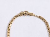 a close up of a gold chain bracelet on a white surface