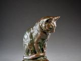 a bronze statue of a cat sitting on top of a rock