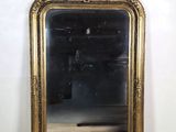 un miroir au cadre doré ouvragé posé sur une table en bois