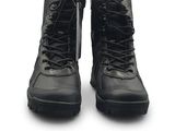 une paire de bottes militaires noires posées sur une surface blanche, sur fond blanc