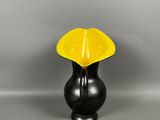 vase jaune et noir avec un socle noir sur un fond gris