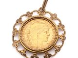 un gros plan d'une pièce d'or sertie dans un pendentif, sur fond blanc