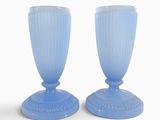 une paire de vases en verre bleu posés sur une surface blanche, sur fond blanc