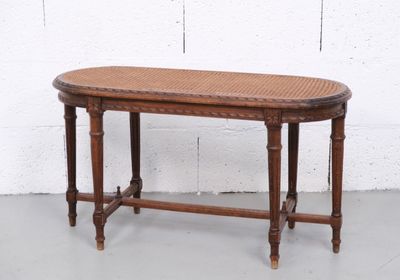 une petite table avec un plateau en osier posée sur un sol blanc