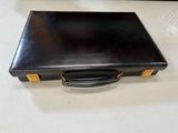 a black briefcase sitting on a table with a yellow handle