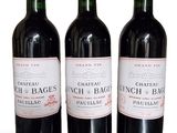 three bottles of red wine sitting next to each other on a white surface