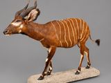 statue d'une antilope posée sur un socle en pierre, sur fond gris