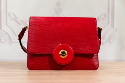 a close up of a red purse on a wooden table
