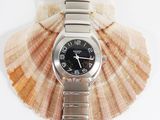 a watch sitting on top of a seashell on a white surface