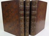 two old books are stacked on top of each other on a white surface