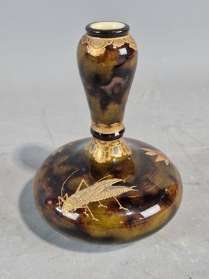 un vase marron et noir sur lequel est représenté un insecte