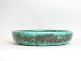a close up of a green bowl on a white surface