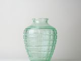 a green glass vase sitting on a white surface