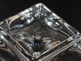a square glass object with a blue bead in the middle