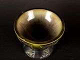 a yellow and black vase sitting on a black surface