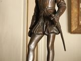 une statue en bronze représentant un homme tenant une épée, posée sur une table