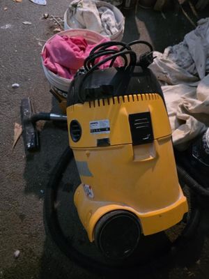 un aspirateur jaune posé par terre à côté d'un tas de vêtements
