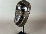 a close up of a sculpture of a mask on a stand