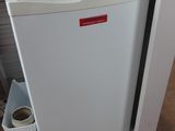 un petit réfrigérateur blanc dans le coin d'une pièce
