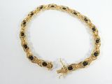a close up of a gold bracelet with black stones on it