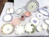 many plates and bowls on a table with a white table cloth