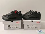 two pairs of black sneakers sitting on top of a white box
