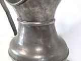 a silver pitcher sitting on a white surface
