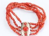 un gros plan sur un collier de perles rouges muni d'un fermoir en argent