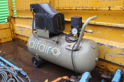 an air compressor sitting on the ground next to a yellow wall
