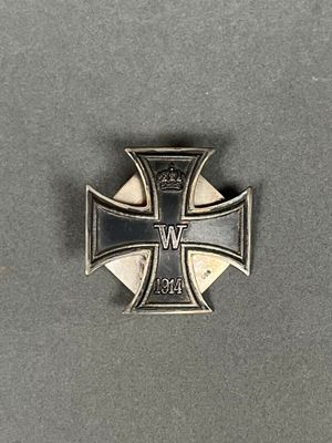 une broche en forme de croix de fer surmontée d'une couronne, posée sur une table