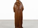 a wooden statue of a man wearing a robe and a hat