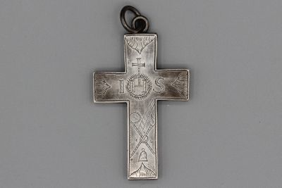 une vieille croix en argent, ornée d'une croix, posée sur une surface grise