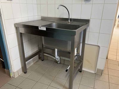 un évier en acier inoxydable dans le coin d'une toilette publique