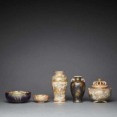 a group of asian vases and bowls on a gray surface