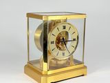 une horloge en or posée sur une surface blanche