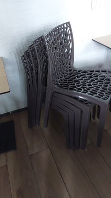 several plastic chairs and a table in a room with wood flooring
