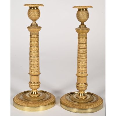 a pair of brass candlesticks with a bird on top of them