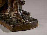 bronze statue of a man sitting on a rock with his foot on the ground
