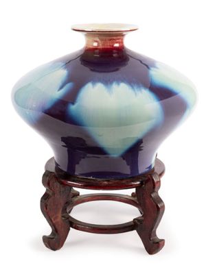 un vase bleu et blanc posé sur un support en bois