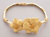 gold bracelet with flowers on it on a gray surface