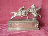 bronze figurine of two men riding horses on a wooden base