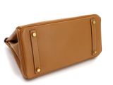 the large tan leather bag is sitting on a white surface