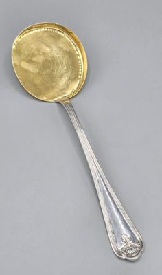 une cuillère en argent avec un couvercle en or et un manche de cuillère