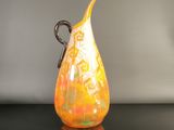 a yellow and orange vase sitting on a black table