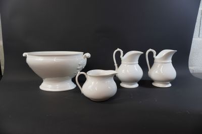 three white pitchers and a bowl on a black table