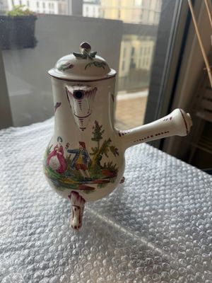 une petite théière avec une anse, posée sur une table