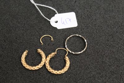 deux paires de boucles d'oreilles créoles en or posées sur une surface noire, accompagnées d'une étiquette de prix