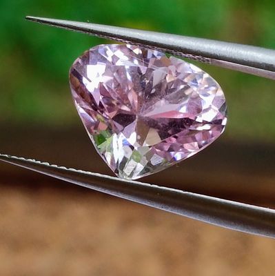 a pink heart shaped diamond being held by a pair of pliers