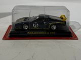 a toy car in a glass case on a white surface
