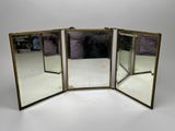 three mirrors with brass frames on a white surface